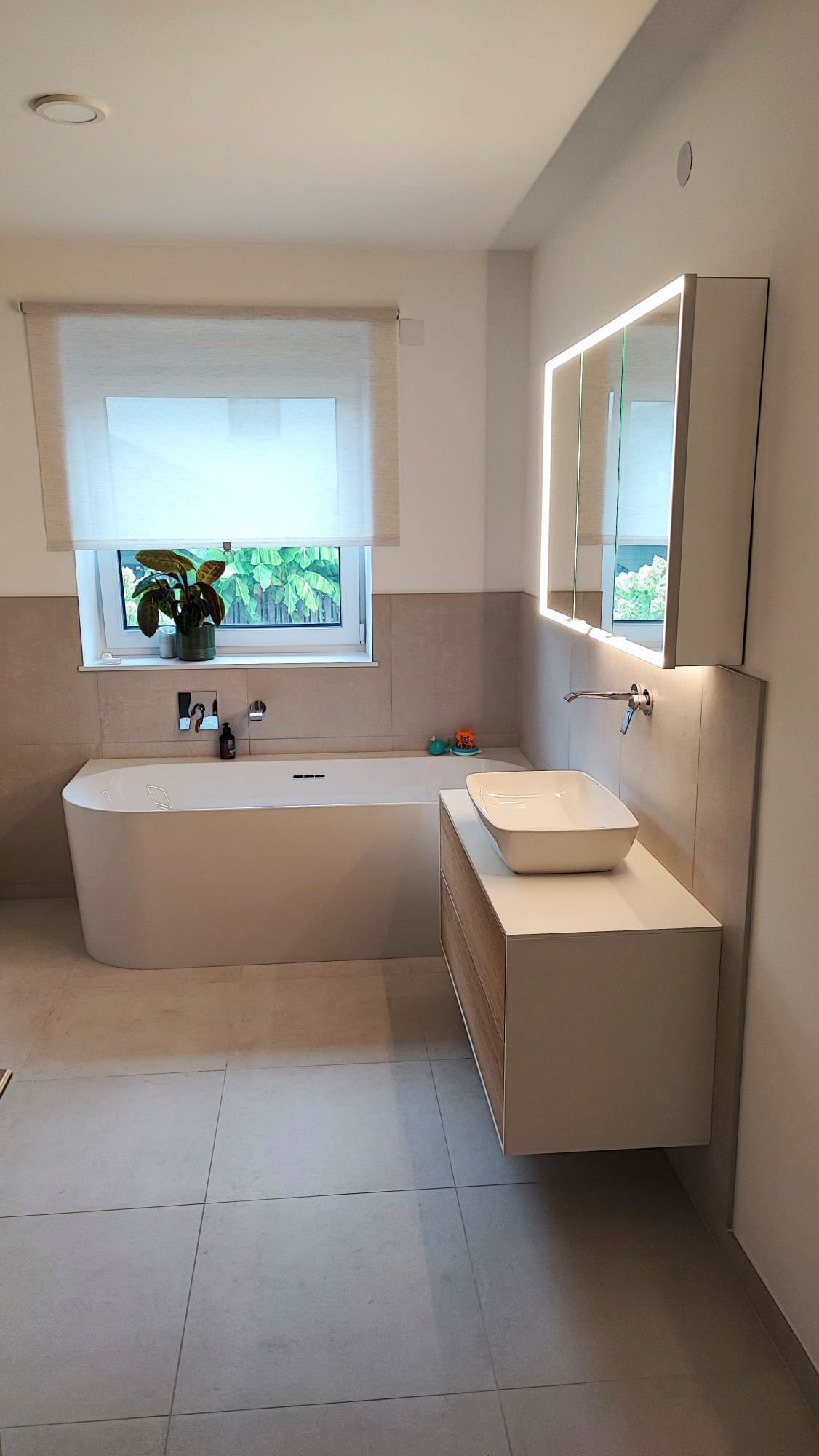 Ein Badezimmer mit Badewanne, Waschbecken, Spiegel und Fenster.