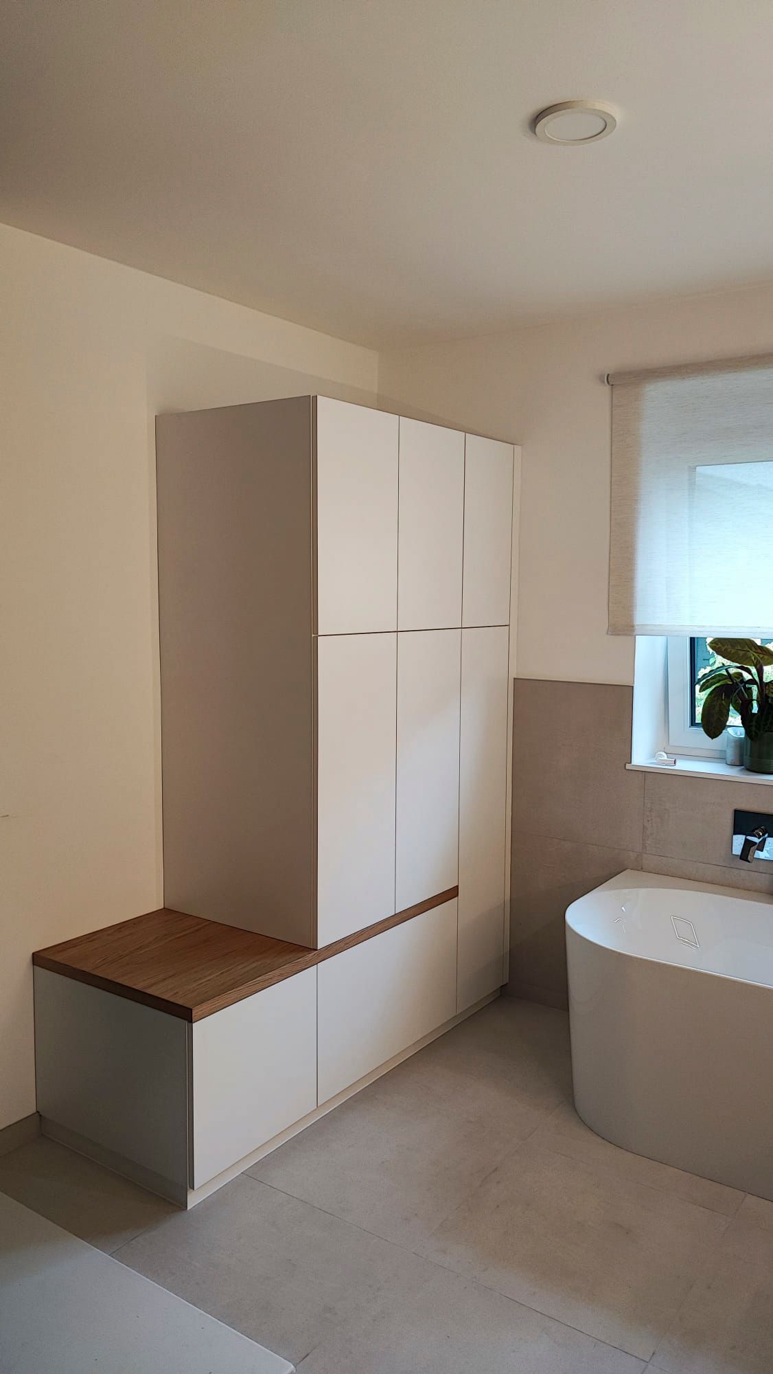 Ein Badezimmer mit Badewanne, Schränken und Fenster.