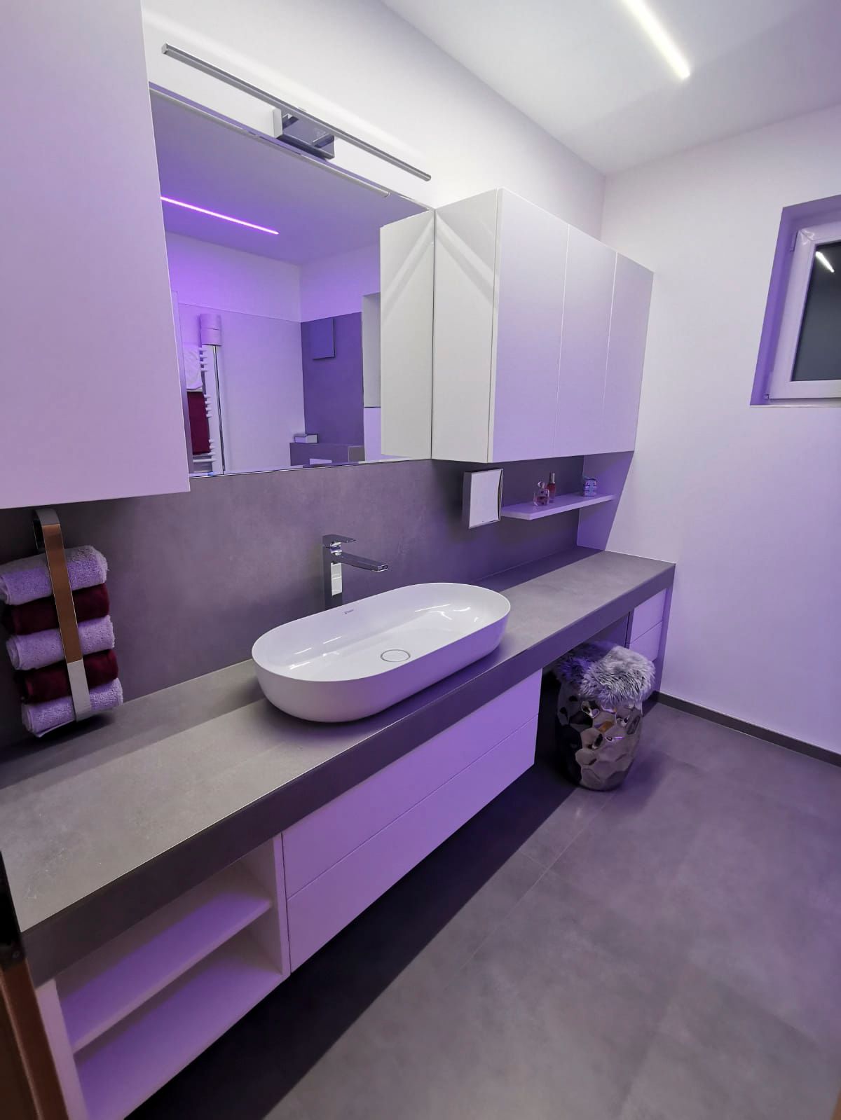 Ein Badezimmer mit Waschbecken, Spiegel und Schränken