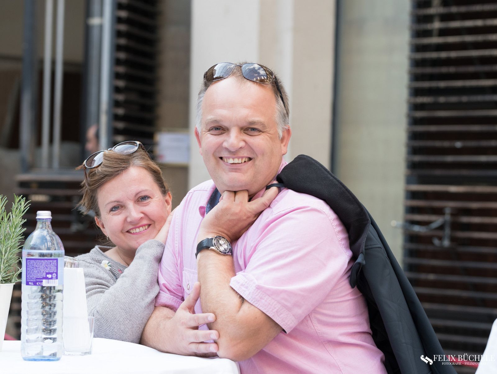 Ein Mann und eine Frau sitzen mit einer Flasche Wasser an einem Tisch.