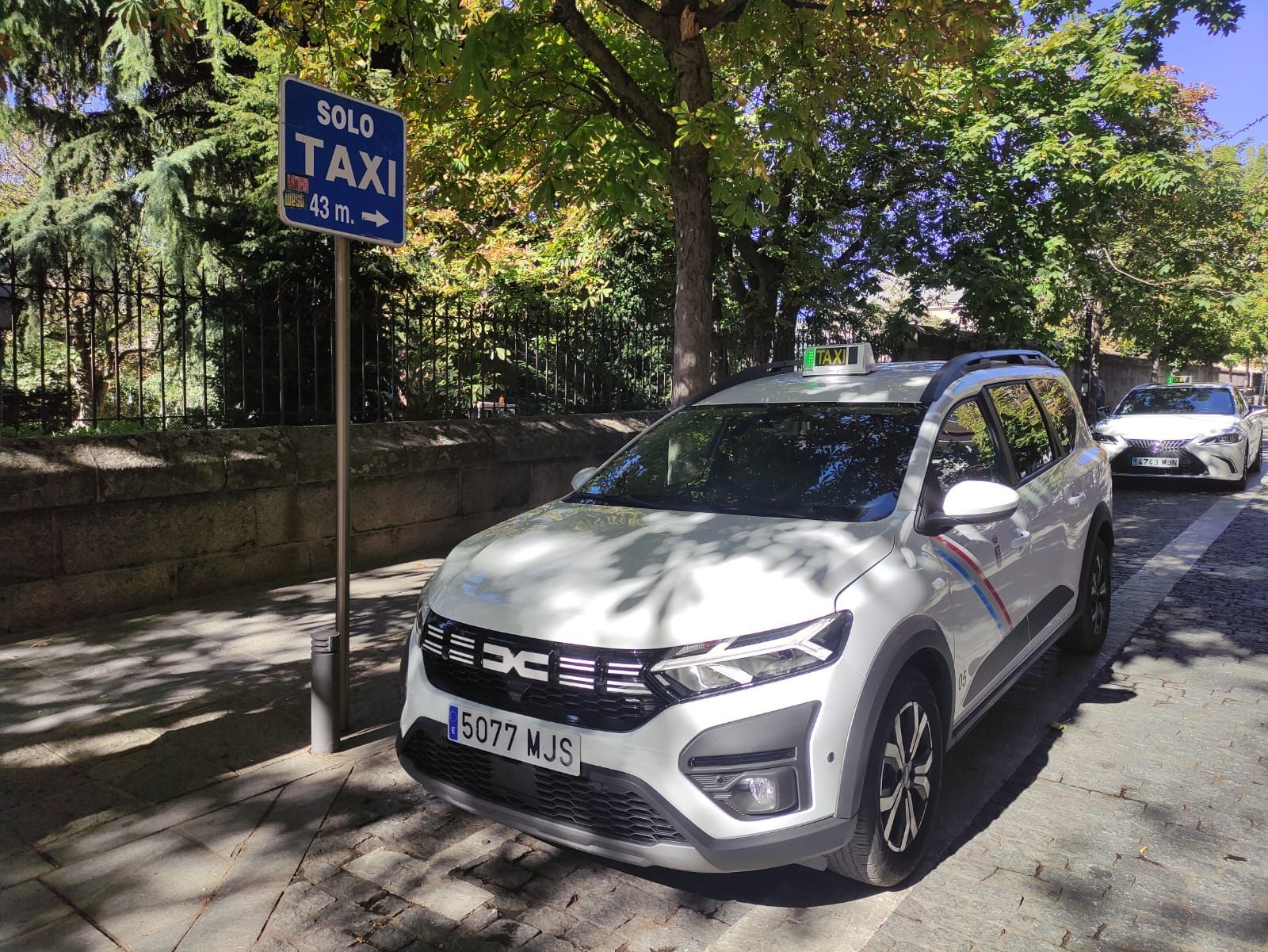 Un coche blanco está aparcado al costado de la carretera al lado de un cartel que dice 