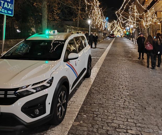 Un taxi blanco está estacionado en una calle adoquinada por la noche.