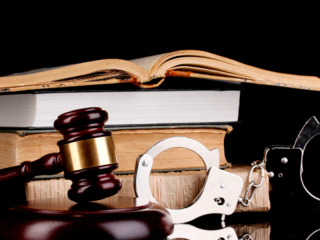 Martillo, esposas y libros de leyes sobre fondo negro, que representan procedimientos legales y justicia.