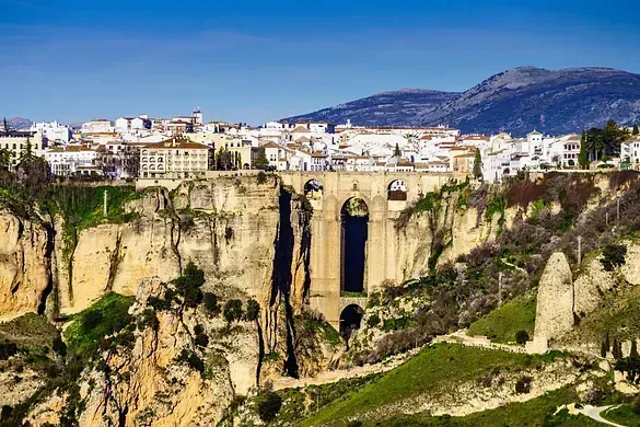Una vista aérea de un puente sobre un acantilado con una ciudad al fondo.