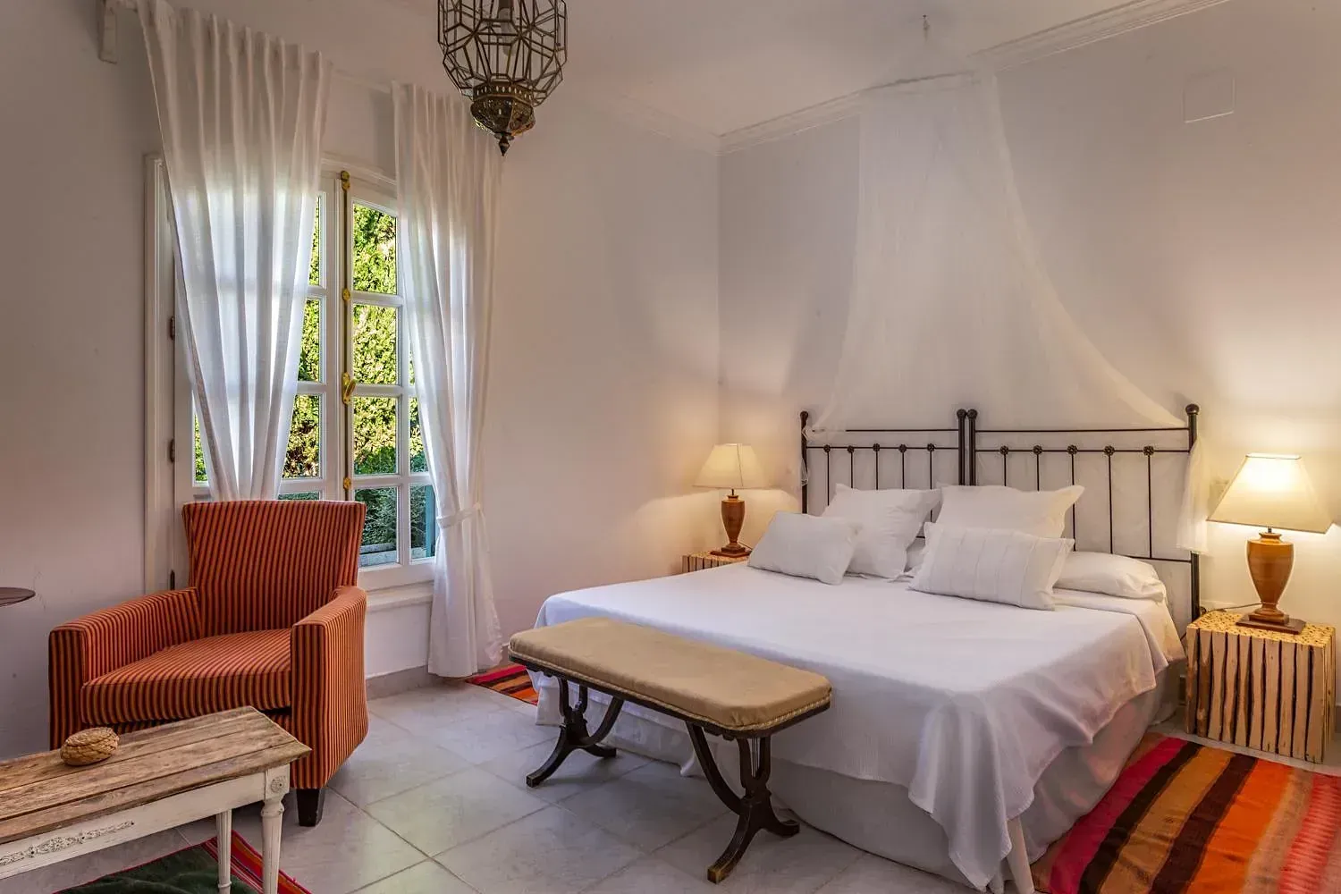 Un dormitorio con una cama, silla, mesa y lámparas.