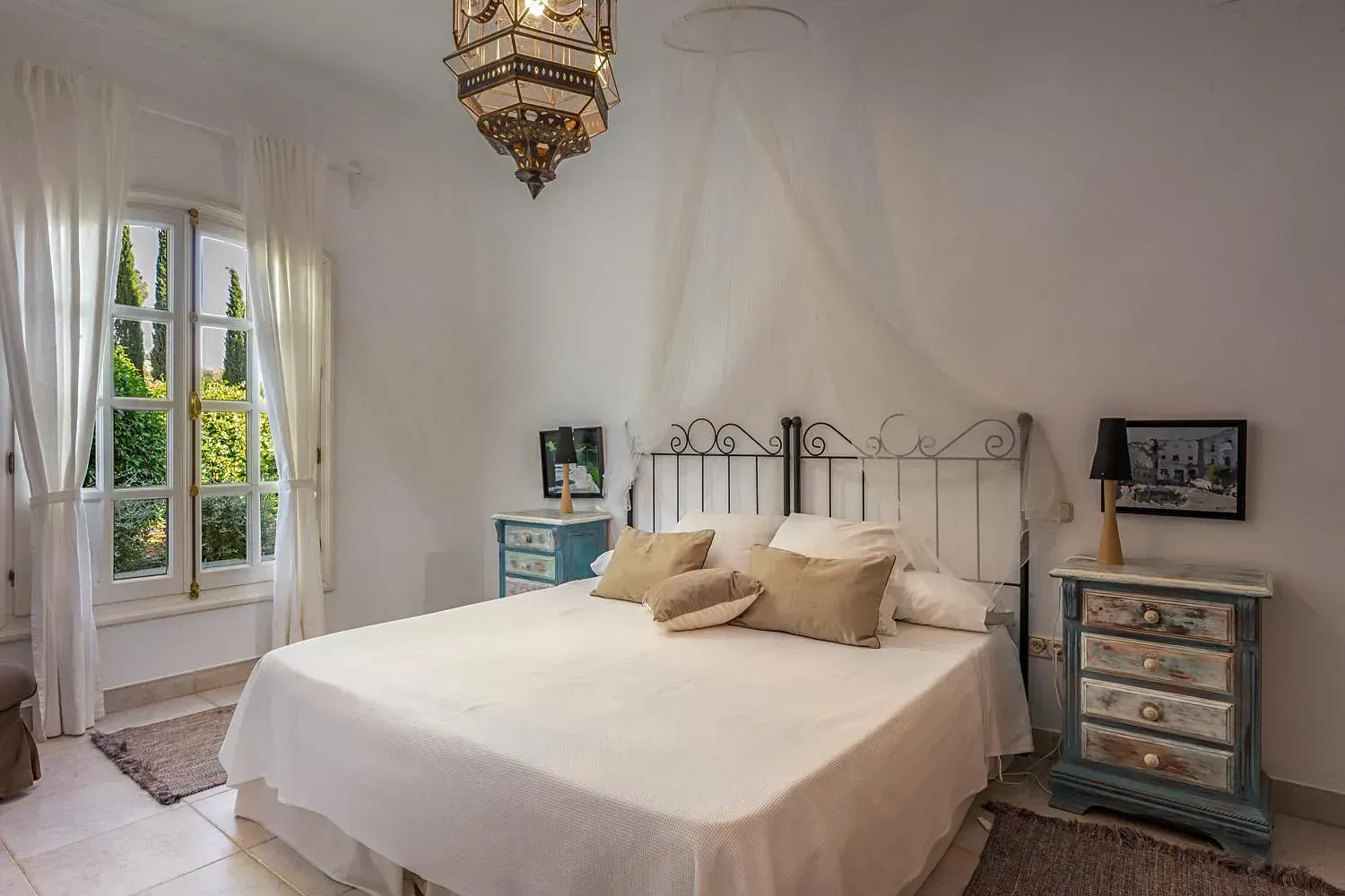 Un dormitorio con una cama grande, mesita de noche y ventana.