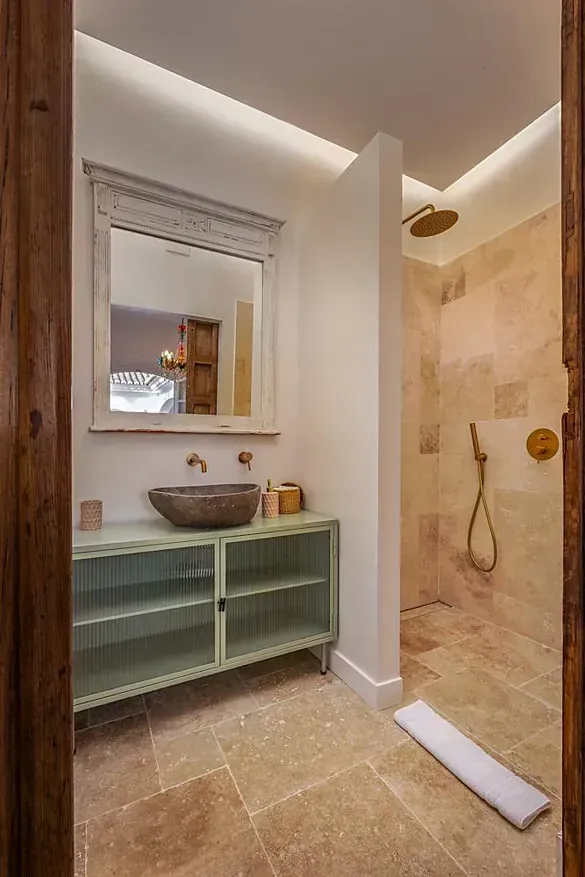 Un baño con lavabo, espejo y ducha.