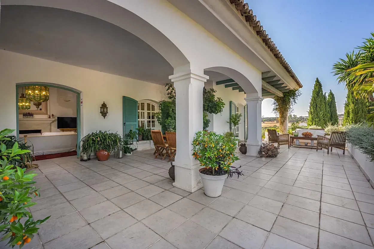 Una gran casa blanca con un gran porche y muchas plantas en macetas.