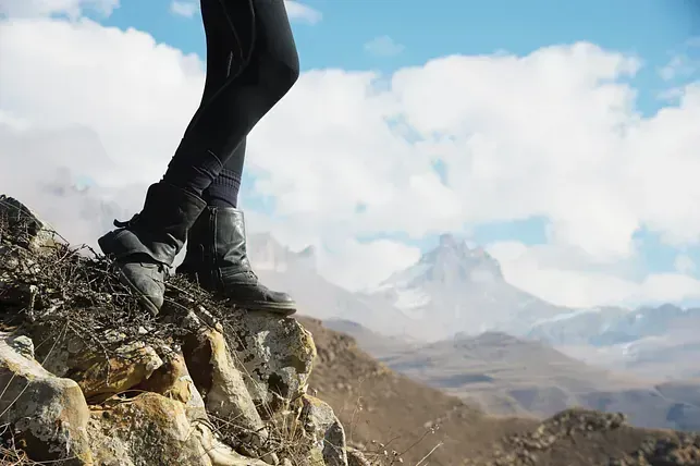 Una persona está parada en la cima de una montaña rocosa.