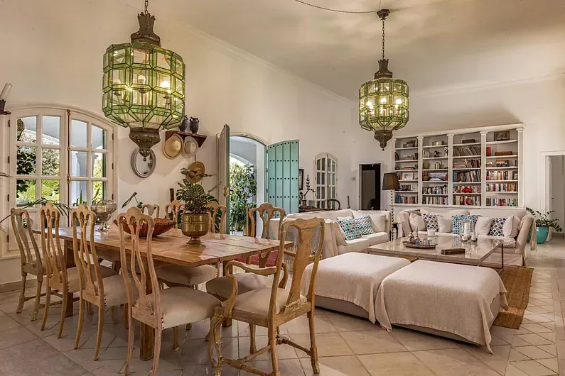 Una sala de estar con una mesa de comedor y sillas, un sofá y una estantería.