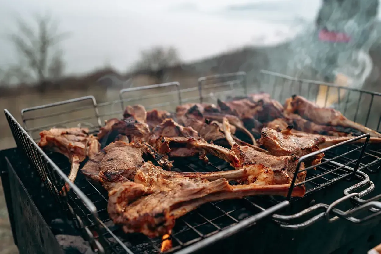 Un montón de carne se está cocinando en una parrilla.