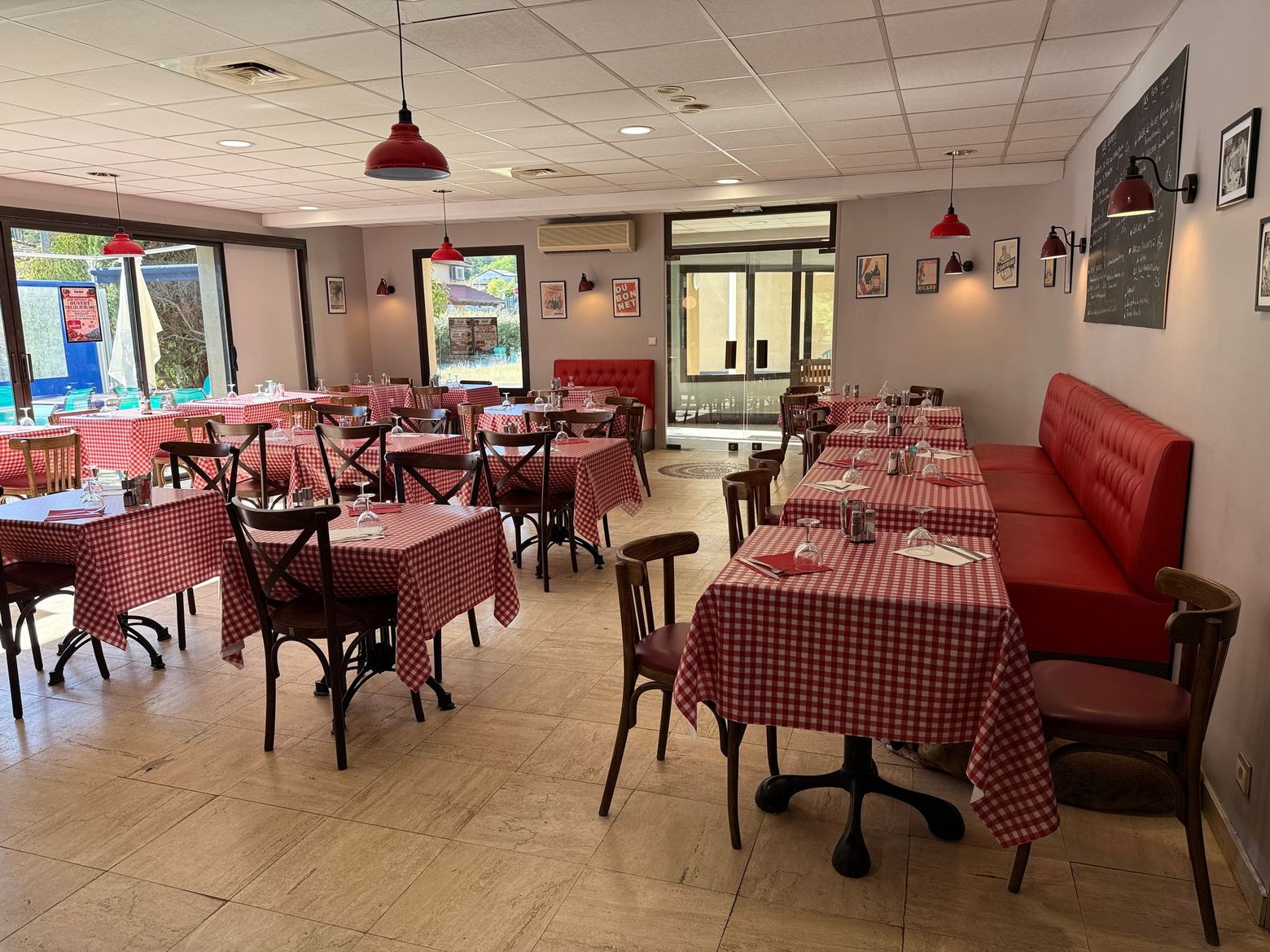 Salle à manger de restaurant vide avec tables à damier rouge et blanc et banquettes rouges.