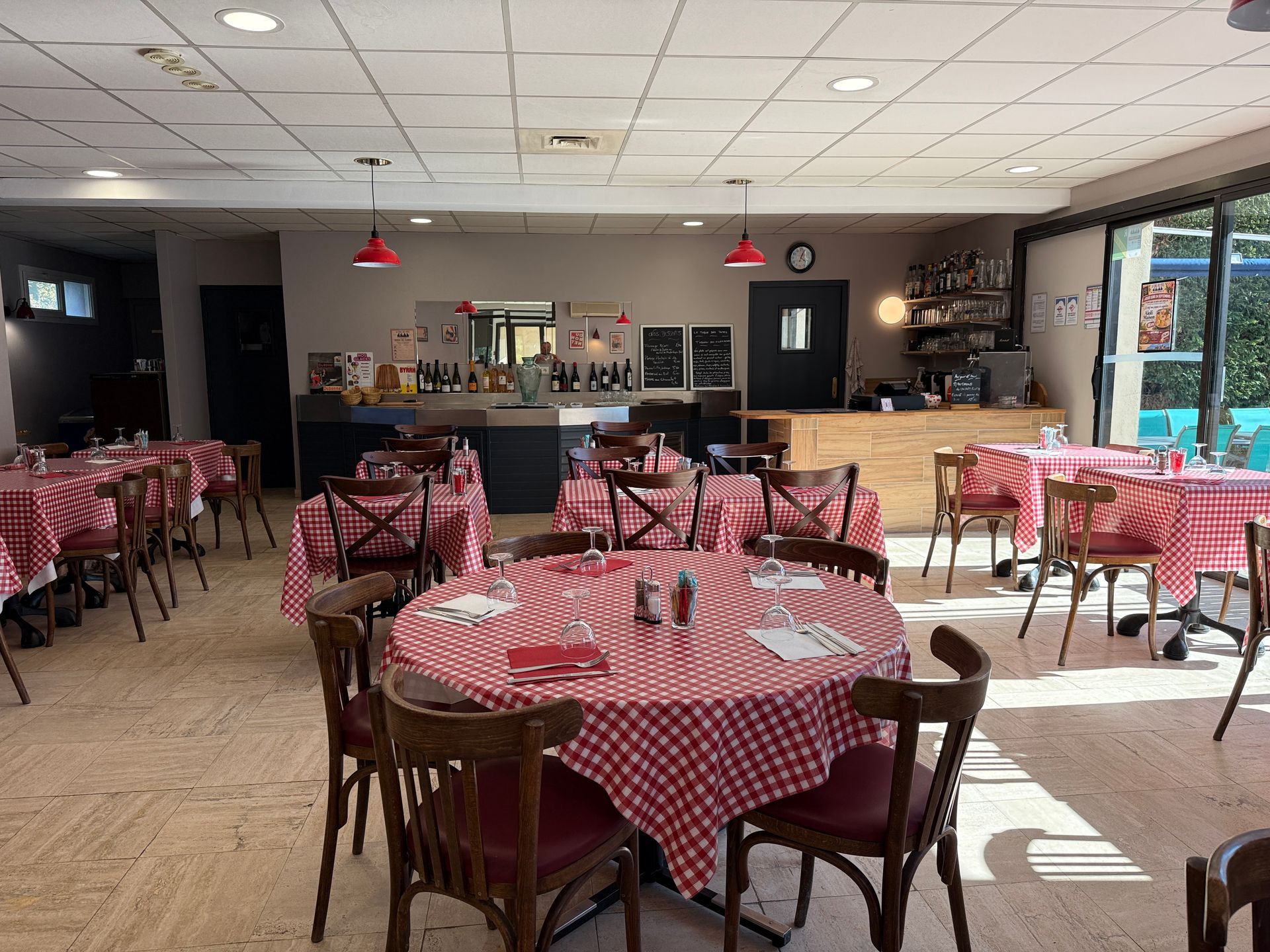 Salle à manger de restaurant vide avec des tables à damier rouge et blanc et des chaises noires.