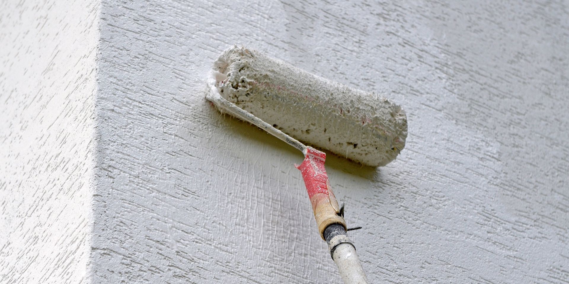 Gros plan sur un rouleau de peinture sur une façade