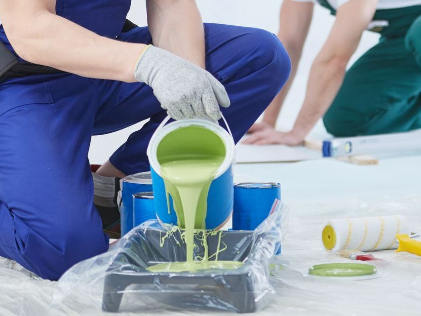 Un peintre qui verse de la peinture dans un bac