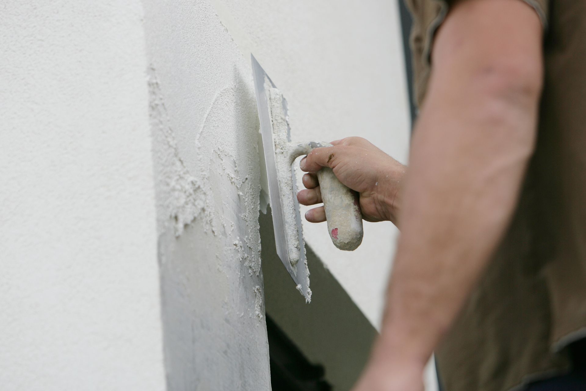 Un professionnel qui applique de l'enduit de façade avec une taloche