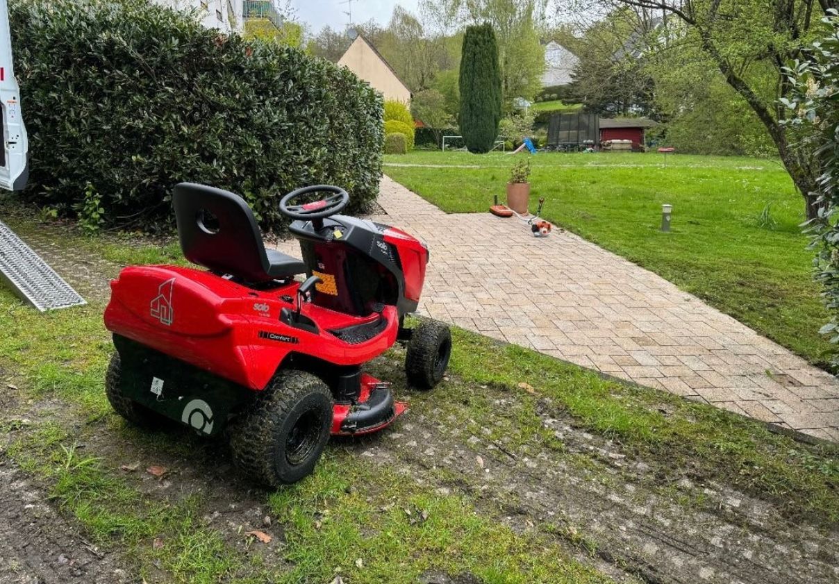 ein fahrbarer Rasenmäher steht in einem großen grünen Garten