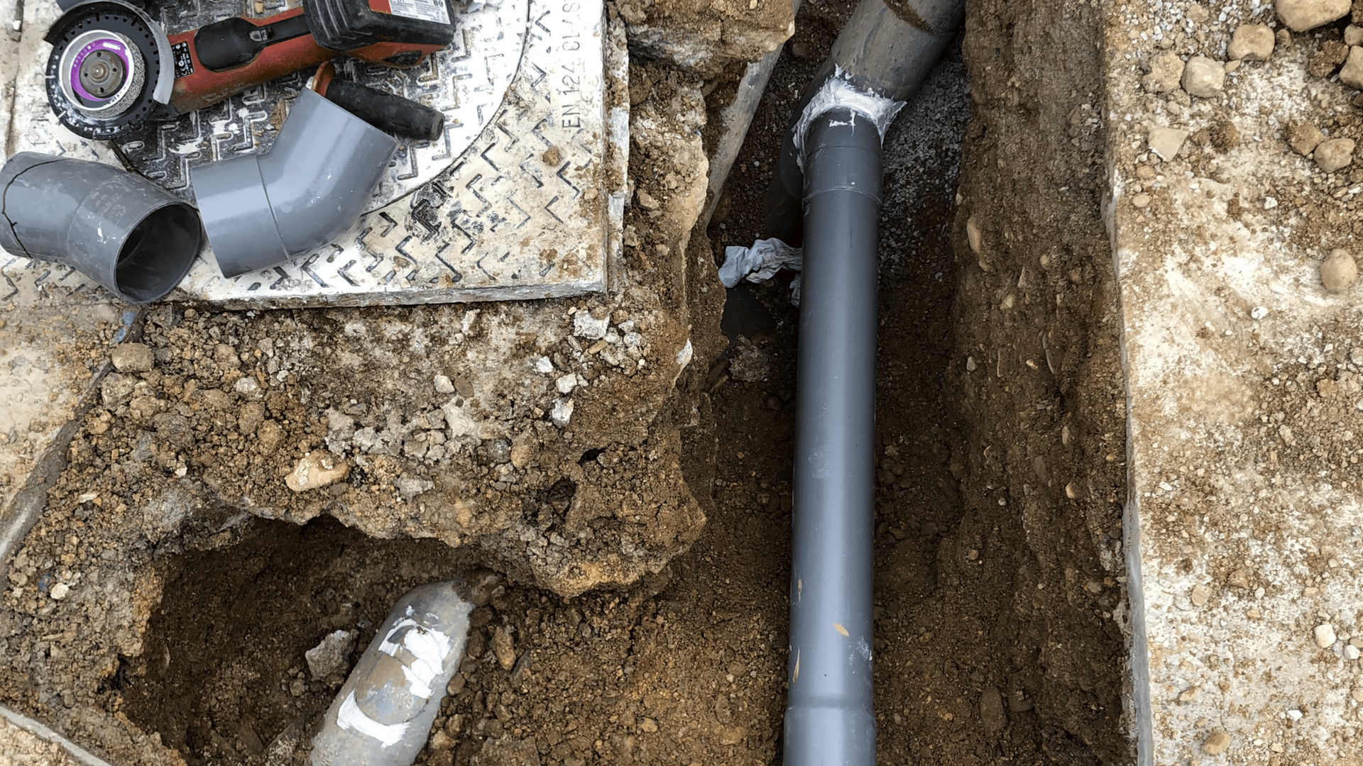 Personne utilisant des pinces pour réparer un tuyau d'eau bleu, probablement à l'extérieur, à proximité de composants d'un puits.