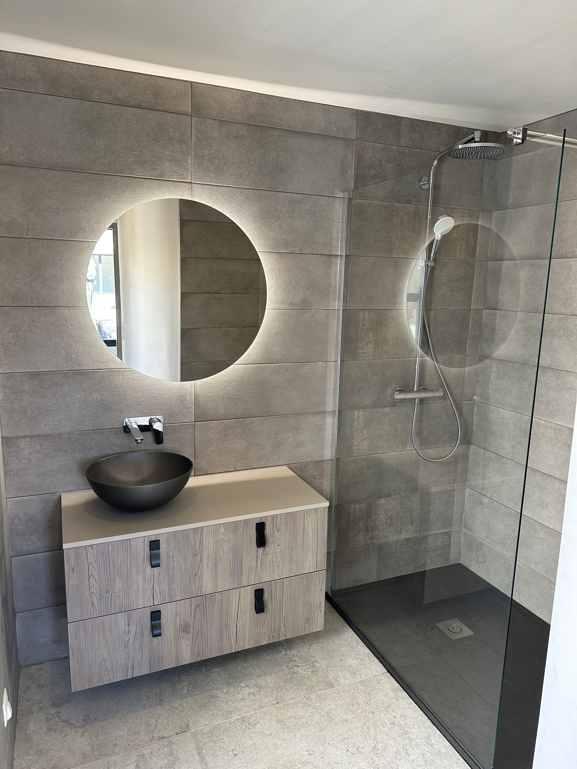 Plombier réparant des tuyaux d'évier avec des outils dans une salle de bains, toilettes en arrière-plan.