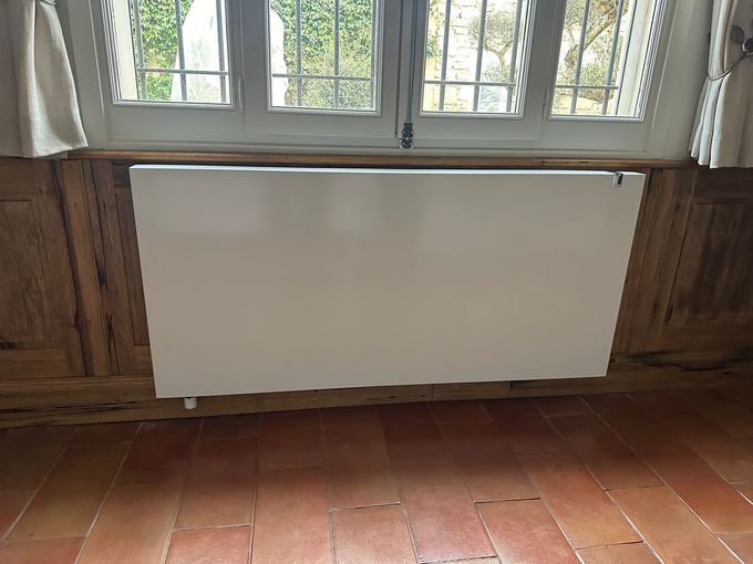 Chauffe-eau blanc avec tuyaux bleu/rouge connectés et collecteur dans un mur encastré.