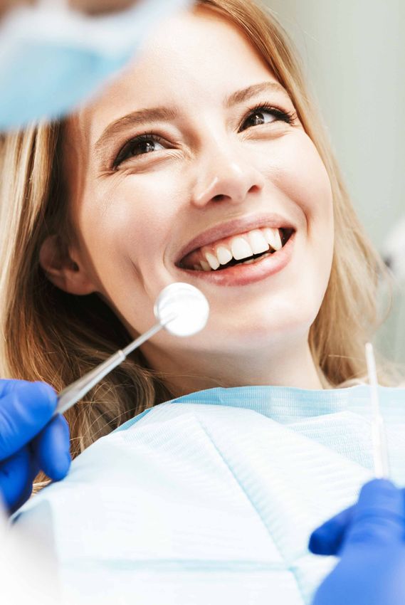 Une jeune femme souriante face à un dentiste tenant des instruments