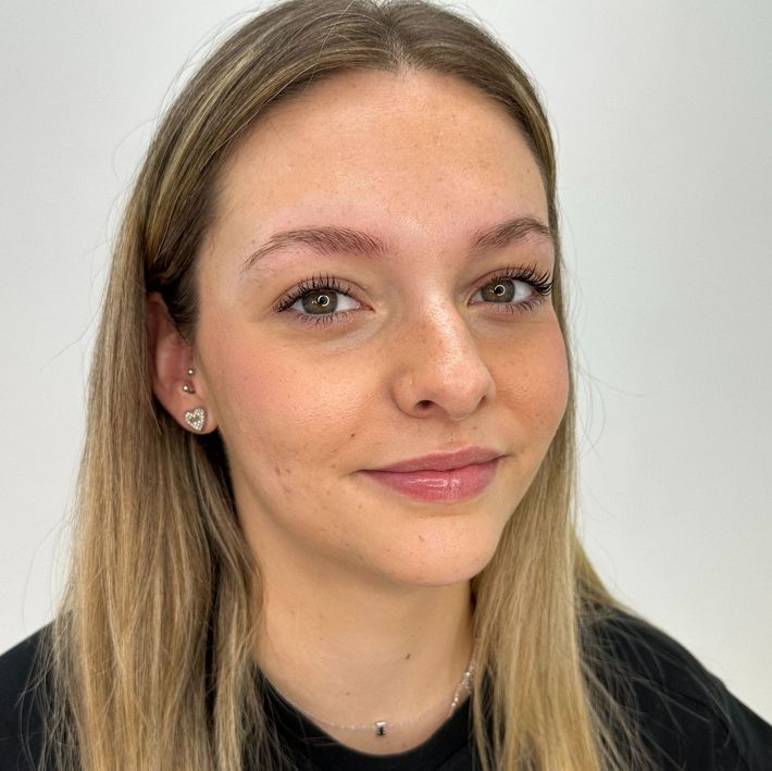 Mujer con cabello rubio y cejas recién microblading sonriendo.