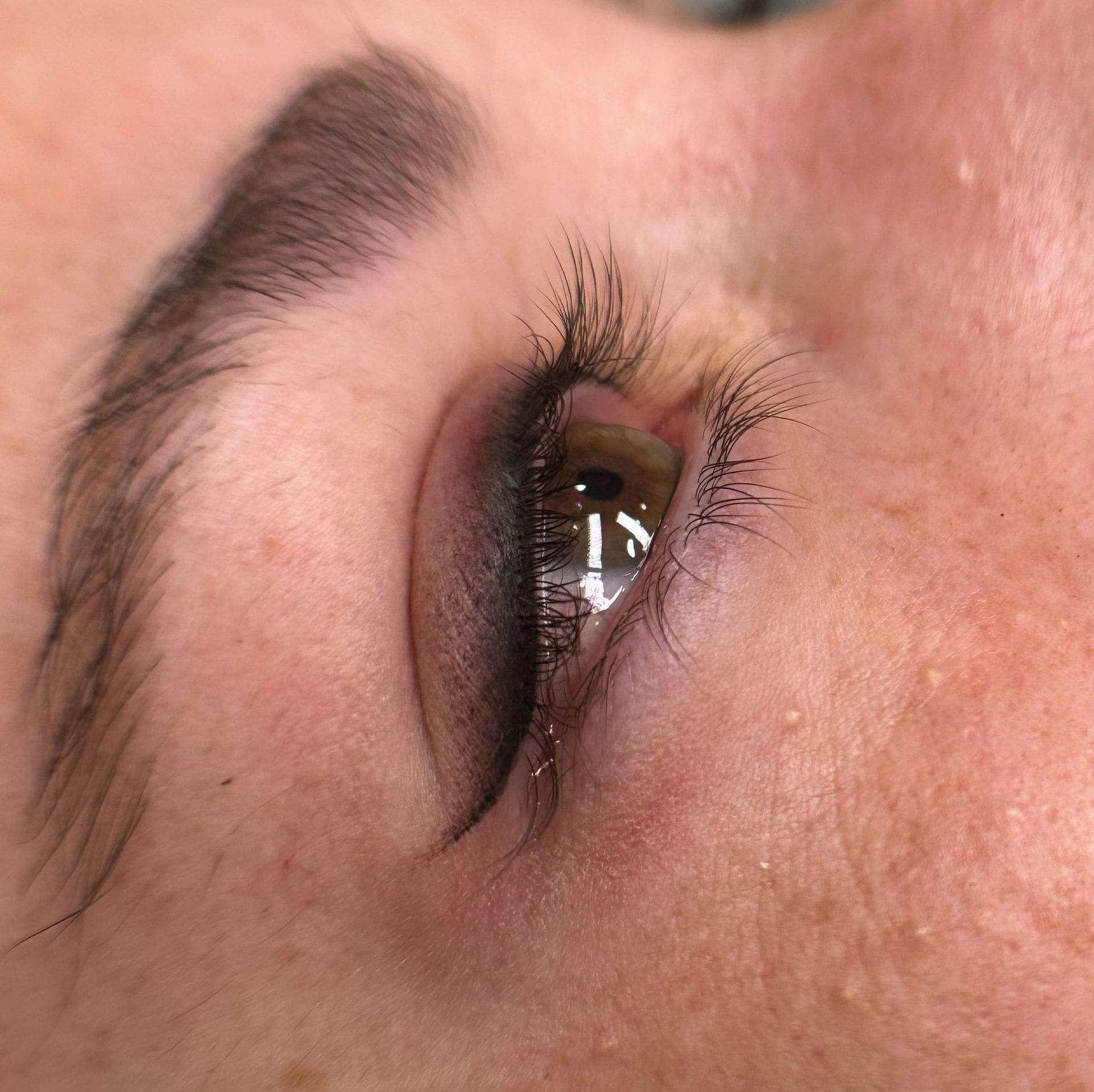 Primer plano de un ojo con delineador de ojos oscuro y ahumado y maquillaje de cejas.