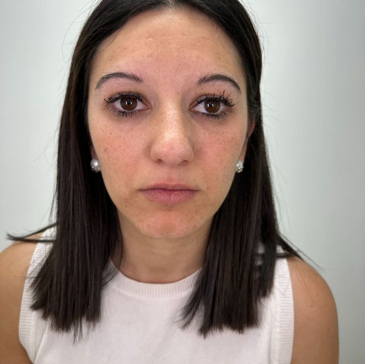 Mujer de cabello oscuro y ojos marrones, vestida con una blusa blanca, mirando directamente a la cámara.