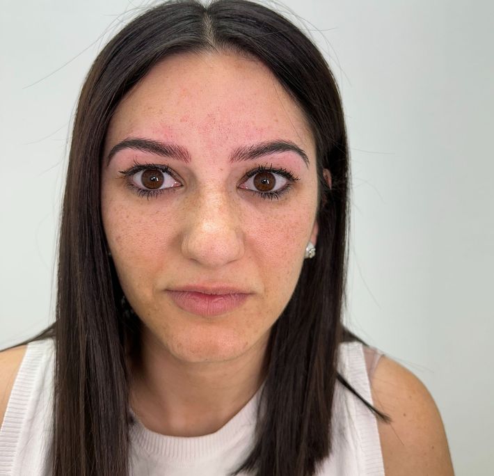 Mujer de cabello oscuro y cejas ligeramente tatuadas; mirando directamente al espectador.