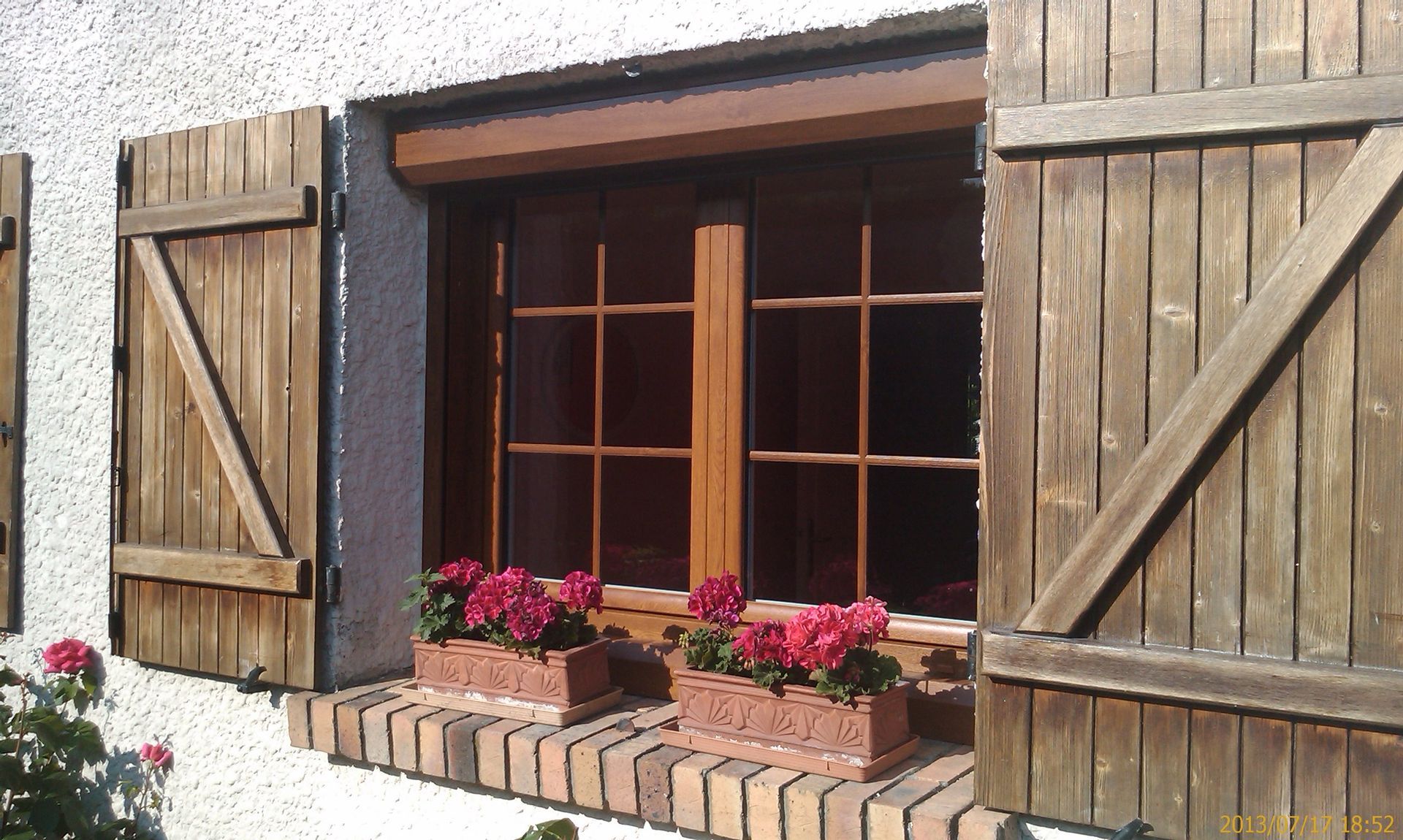 Une fenêtre avec des volets en bois et des pots de fleurs