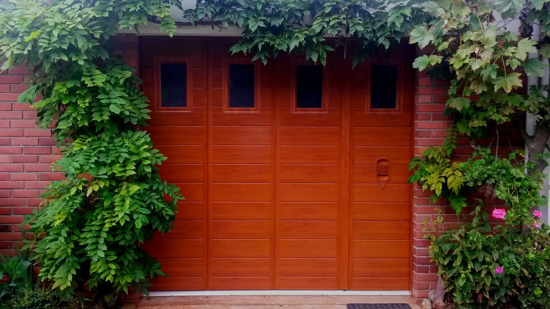 Une porte de garage marron entourée de verdure