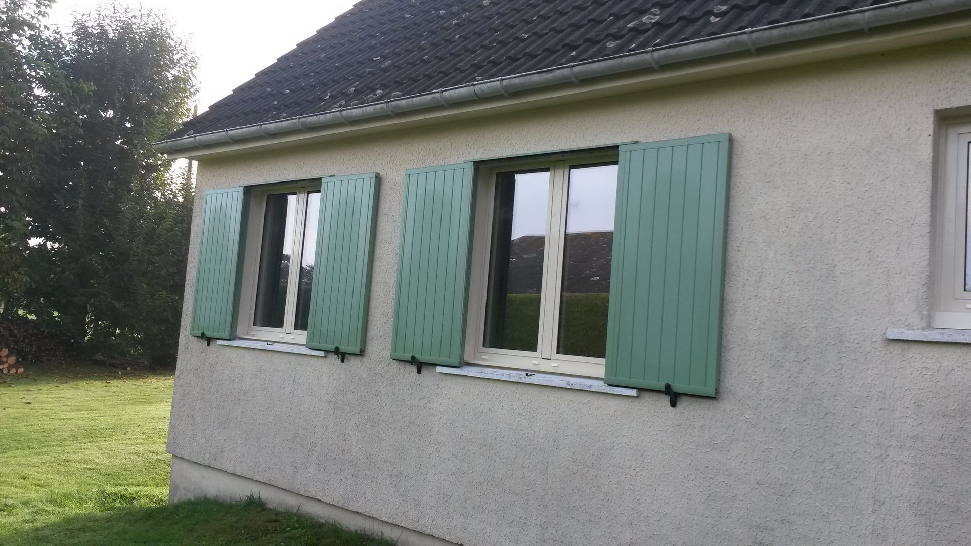 Deux fenêtres avec des volets verts