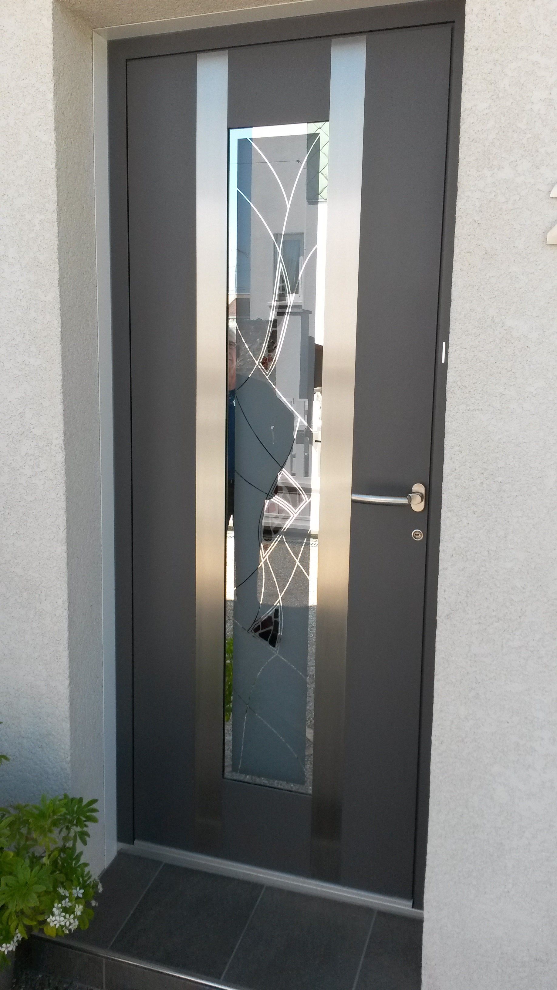 Porte d'entrée en aluminium de couleur grise et mur en briques grises