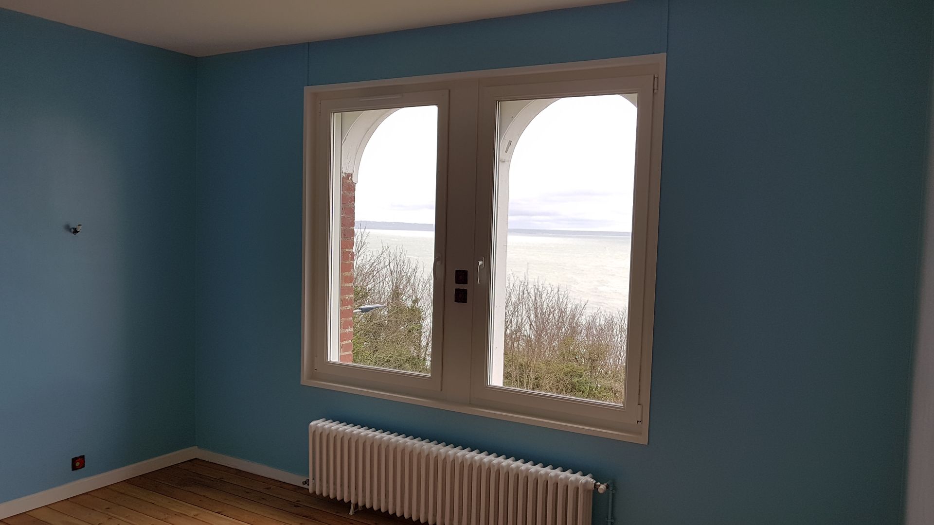 Une double fenêtre dans une pièce peinte en bleue