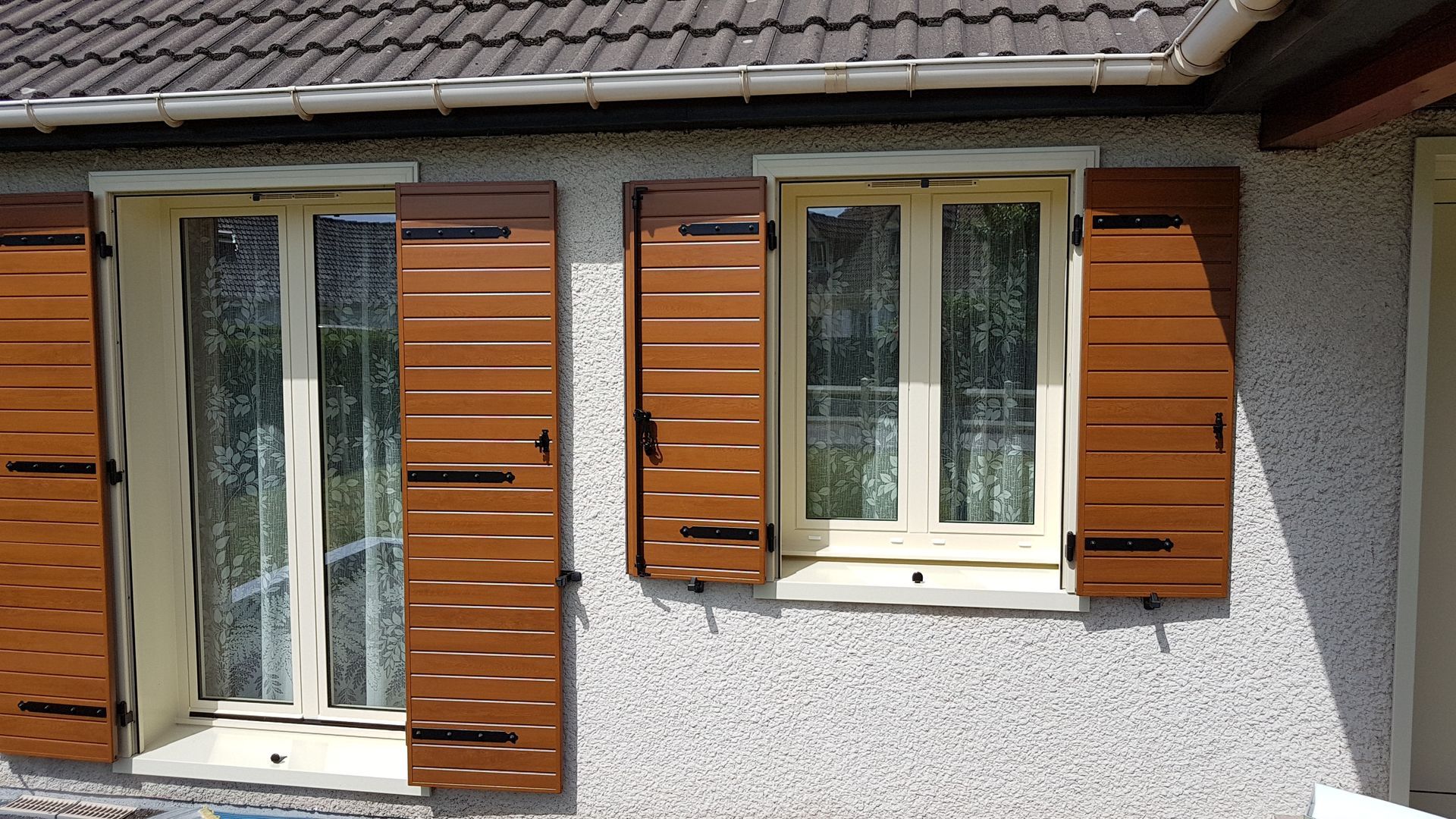 Deux fenêtres de différentes tailles avec des volets marron