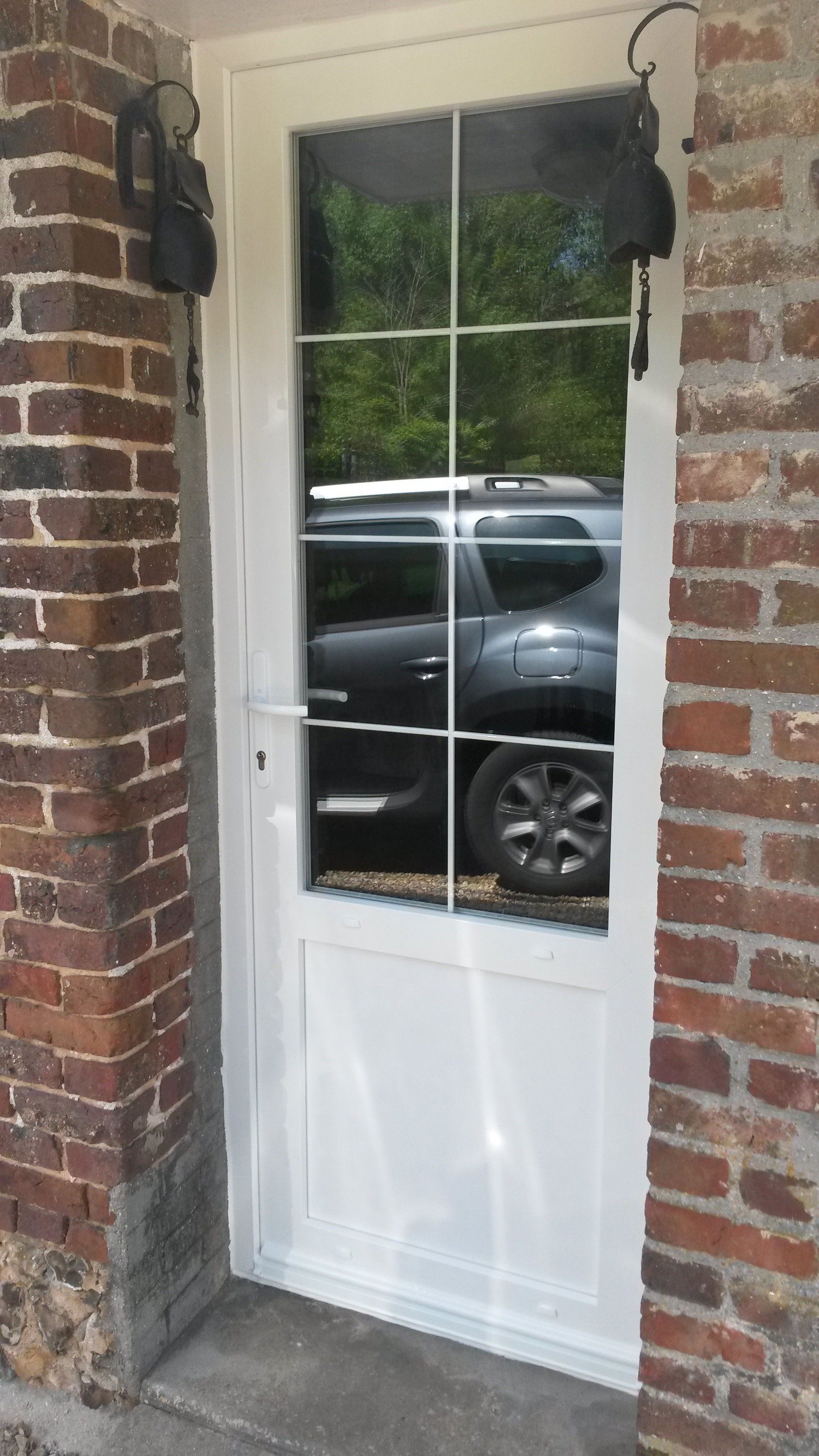 Une porte blanche avec des vitres avec une voiture dans le reflet