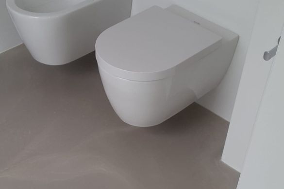Toilette und Bidet vor grauem Betonboden