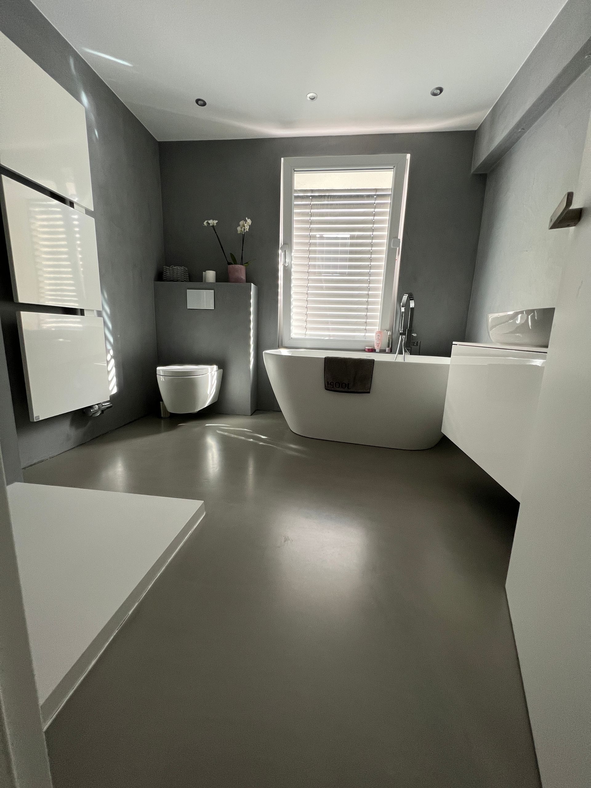 Badewanne und Toilette auf glänzend schwarzem Epoxitboden