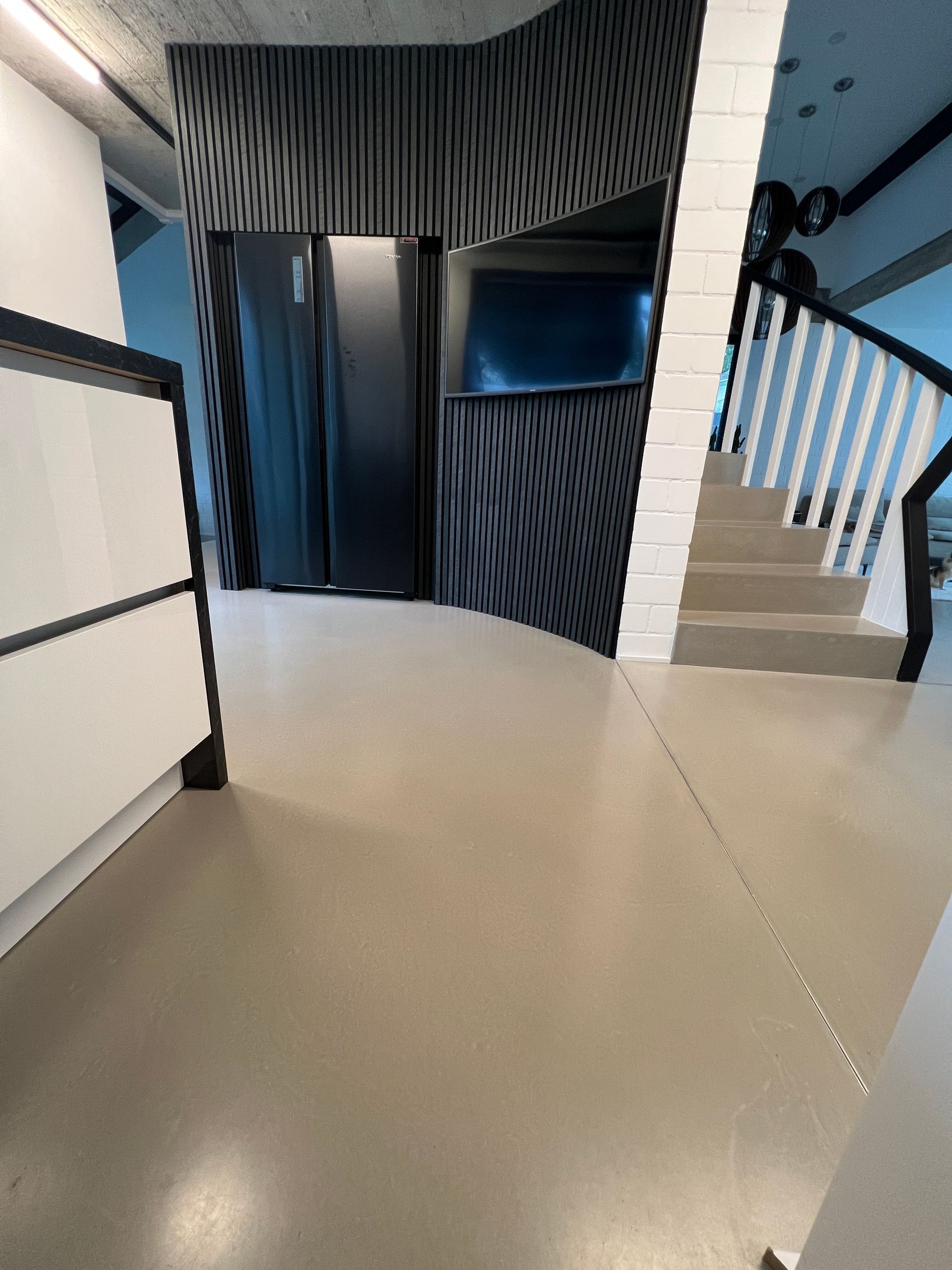 großer, leerer Raum mit Betonboden und breiter Fensterfront