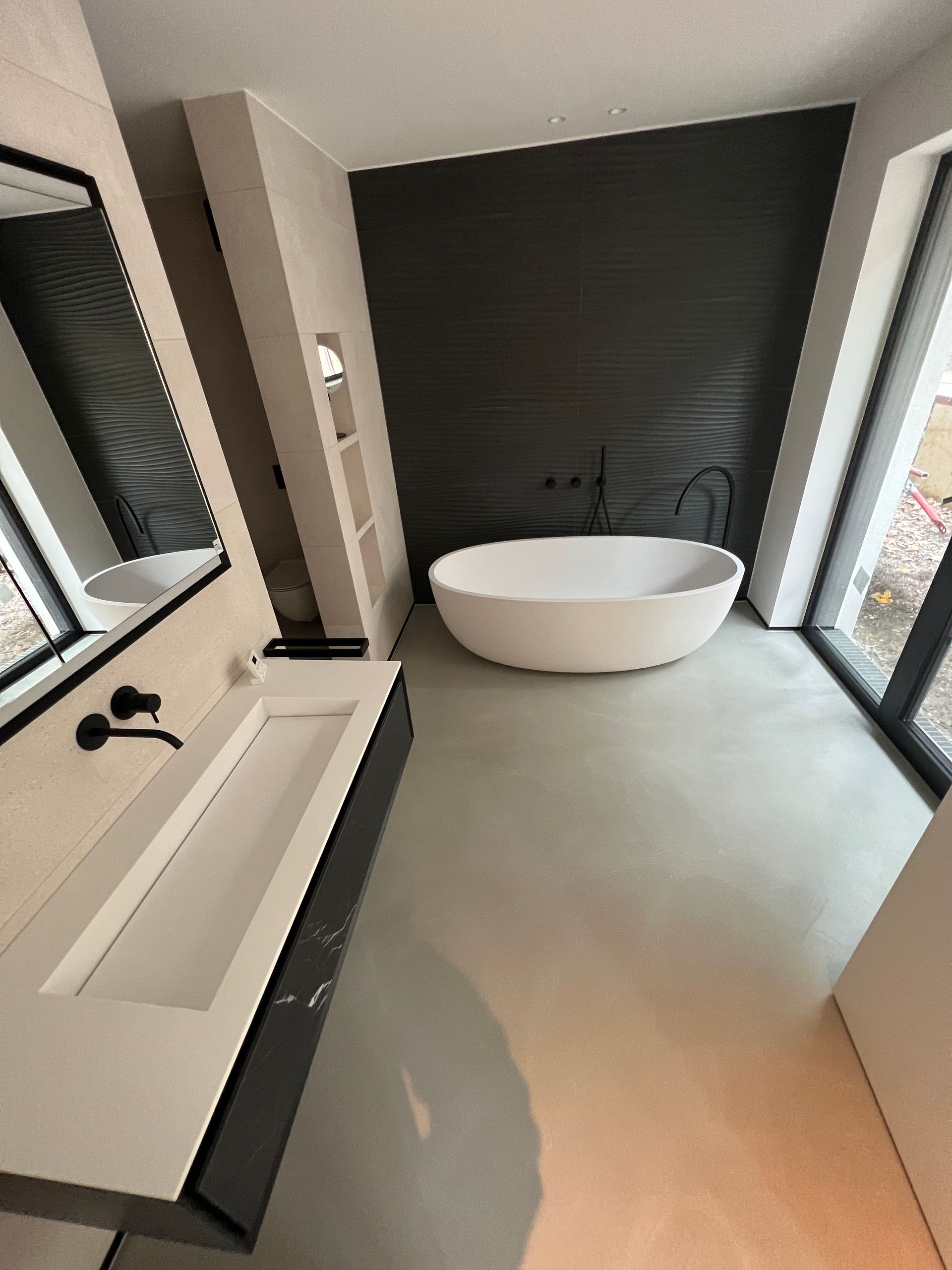 Toilette und Waschbecken vor grauem Betonboden