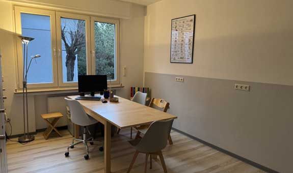 Ein Raum mit einem Tisch und Stühlen und einem Computer darauf.