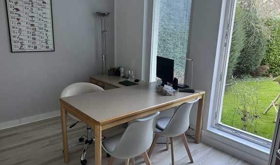 Ein Raum mit einem Tisch und Stühlen und einem Computer darauf.