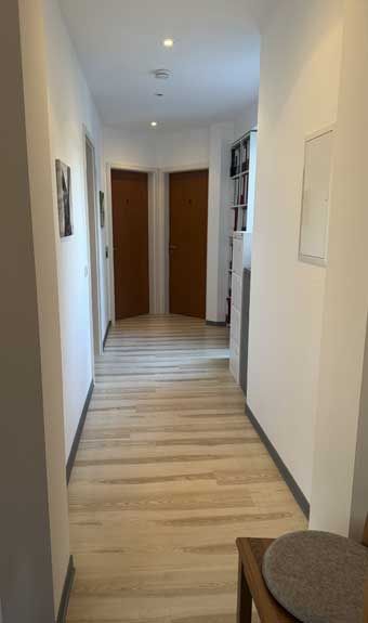 Ein langer Flur mit Holzboden und zwei Türen.