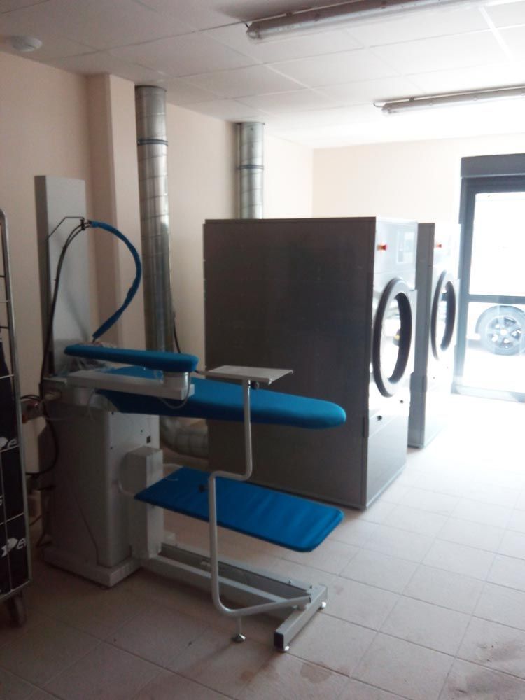 Une buanderie industrielle équipée d'une table à repasser et d'un sèche-linge.