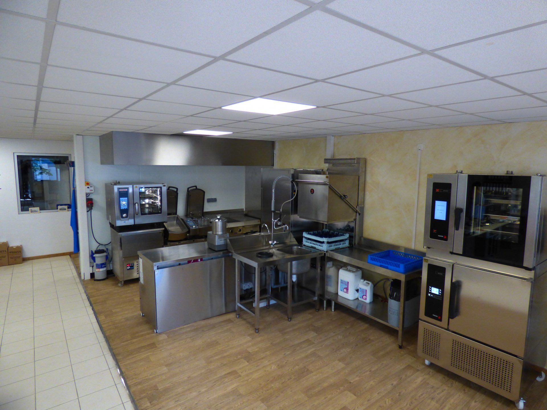 Cuisine professionnelle équipée d'appareils en acier inoxydable et d'une hotte aspirante.