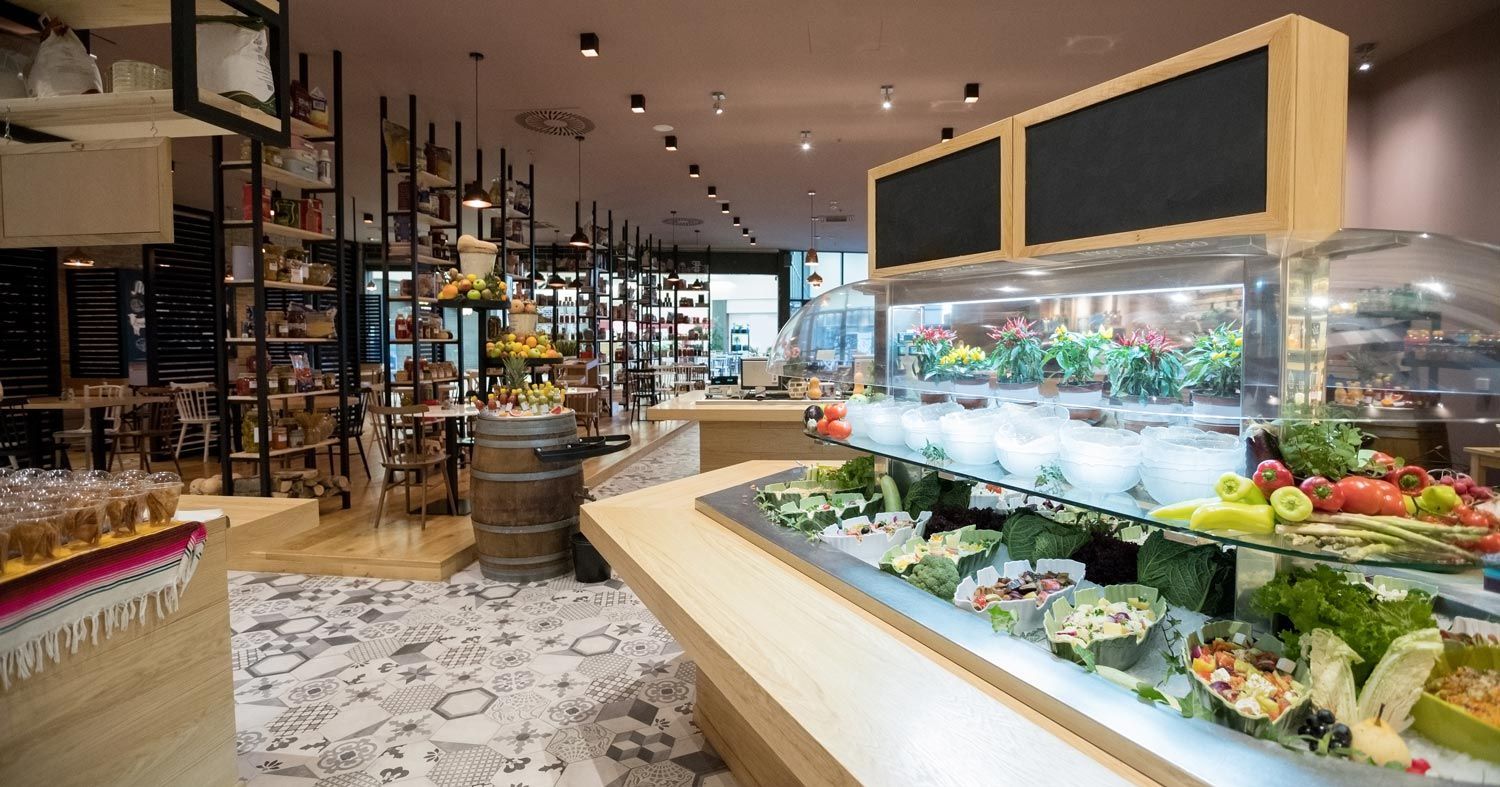 Intérieur de restaurant avec un buffet de salades proposant divers ingrédients frais et un éclairage soigné.