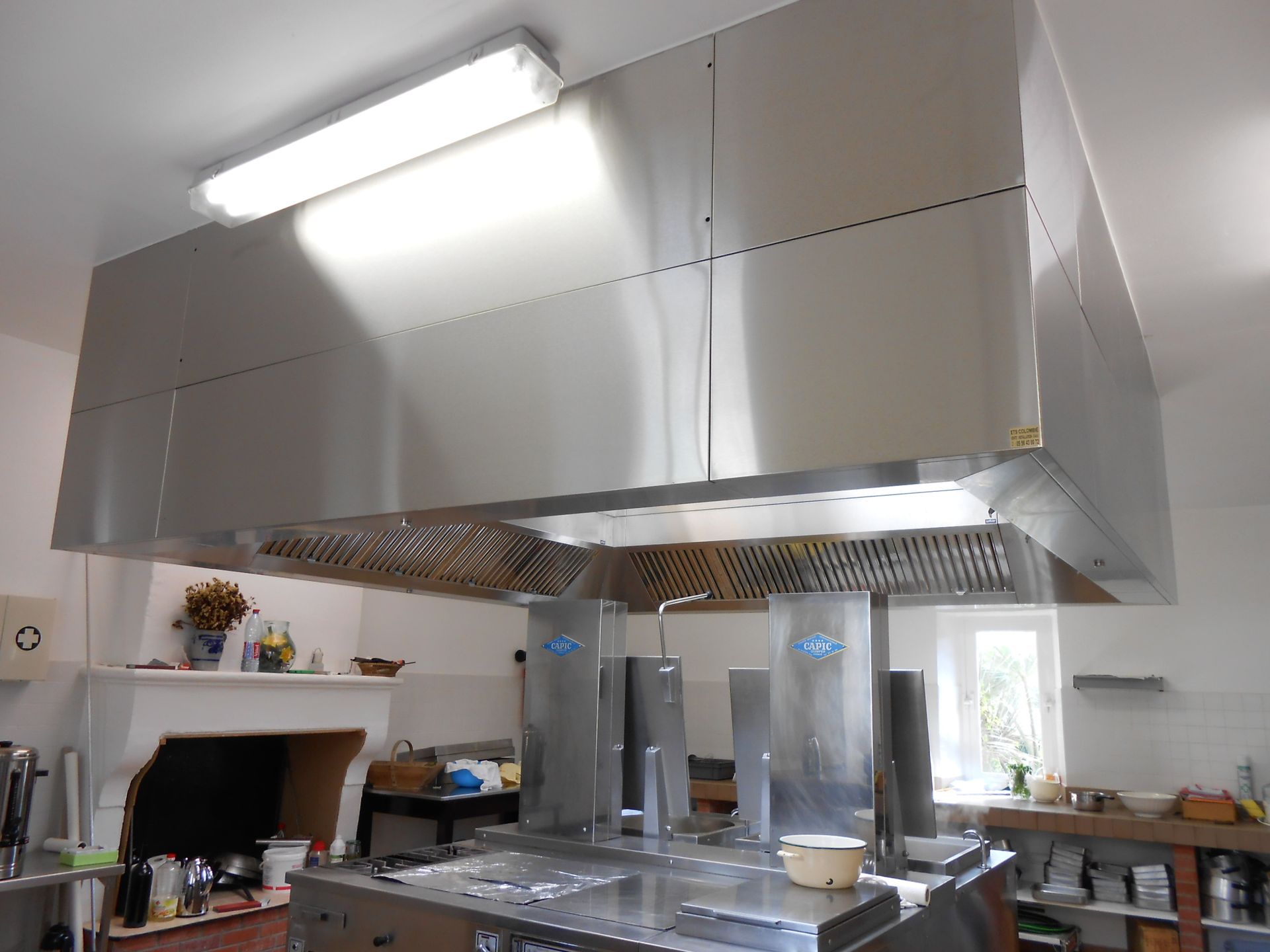 Hotte de cuisine professionnelle en acier inoxydable au-dessus des équipements de cuisson.