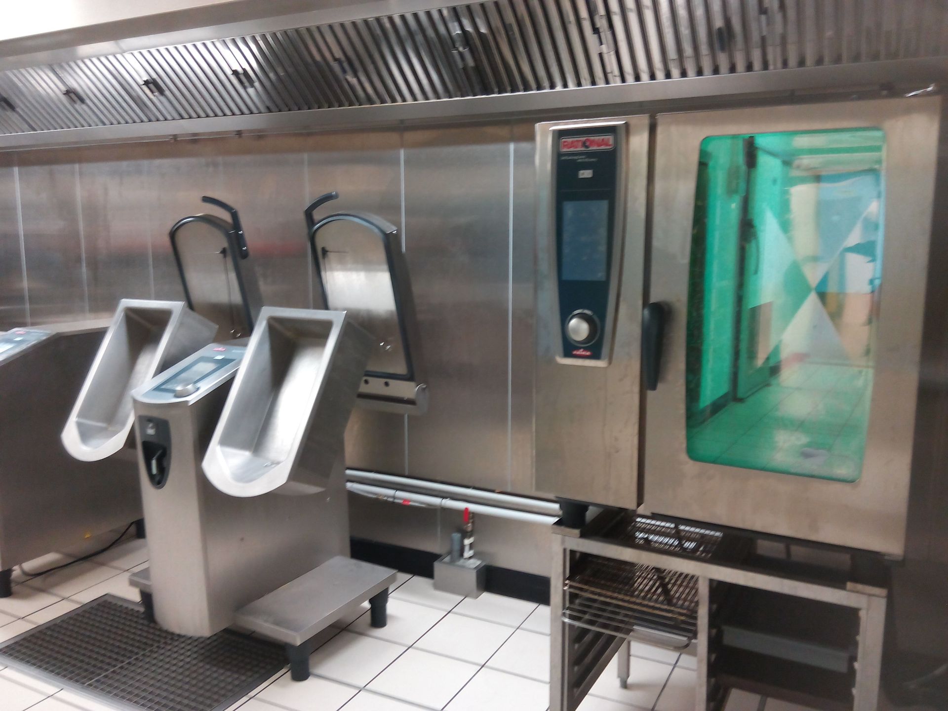 Cuisine professionnelle équipée de matériel en acier inoxydable, comprenant un four à convection et des unités de préparation alimentaire.