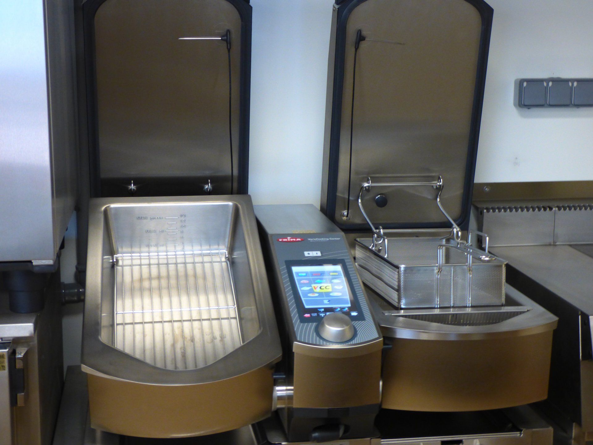 Deux friteuses industrielles, couvercles ouverts, côte à côte, dans une cuisine.