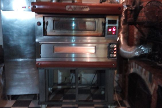 Un four à pizza professionnel à deux compartiments superposés, en acier inoxydable et rouge, sur un support.